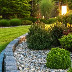 Professionally Landscaped Garden Flower Bed Closeup of Professionally Landscaped Flower Bed with Decorative Green Garden Plants and Evenly Mowed Lawn in the Background.